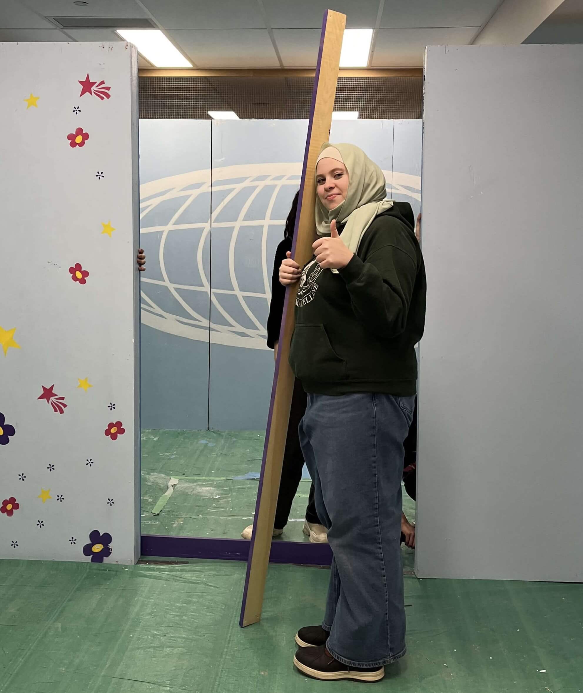 A team member holding a plank of wood in the kiosk.