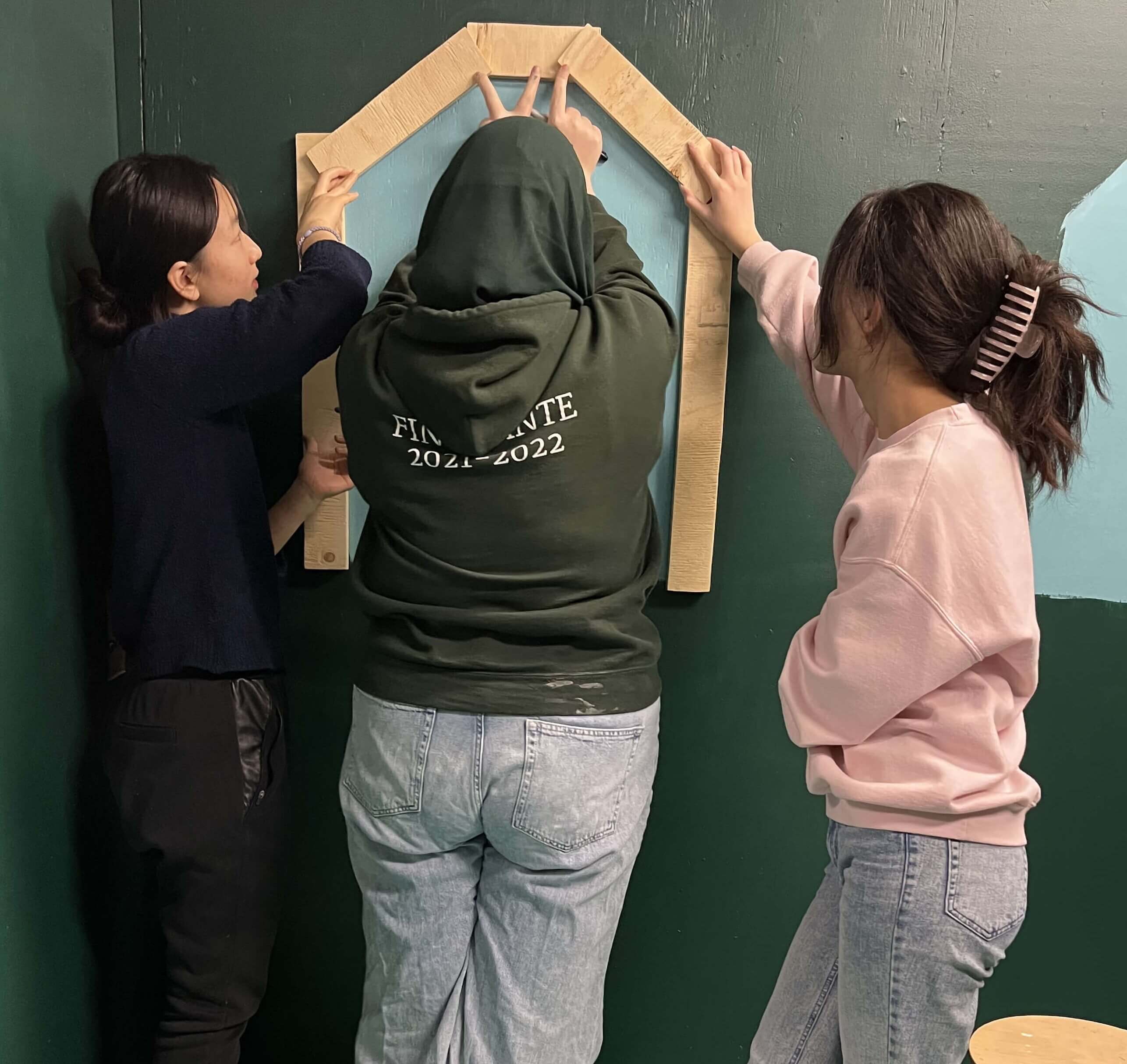 Three team members placing the wooden frames for the kiosk windows.