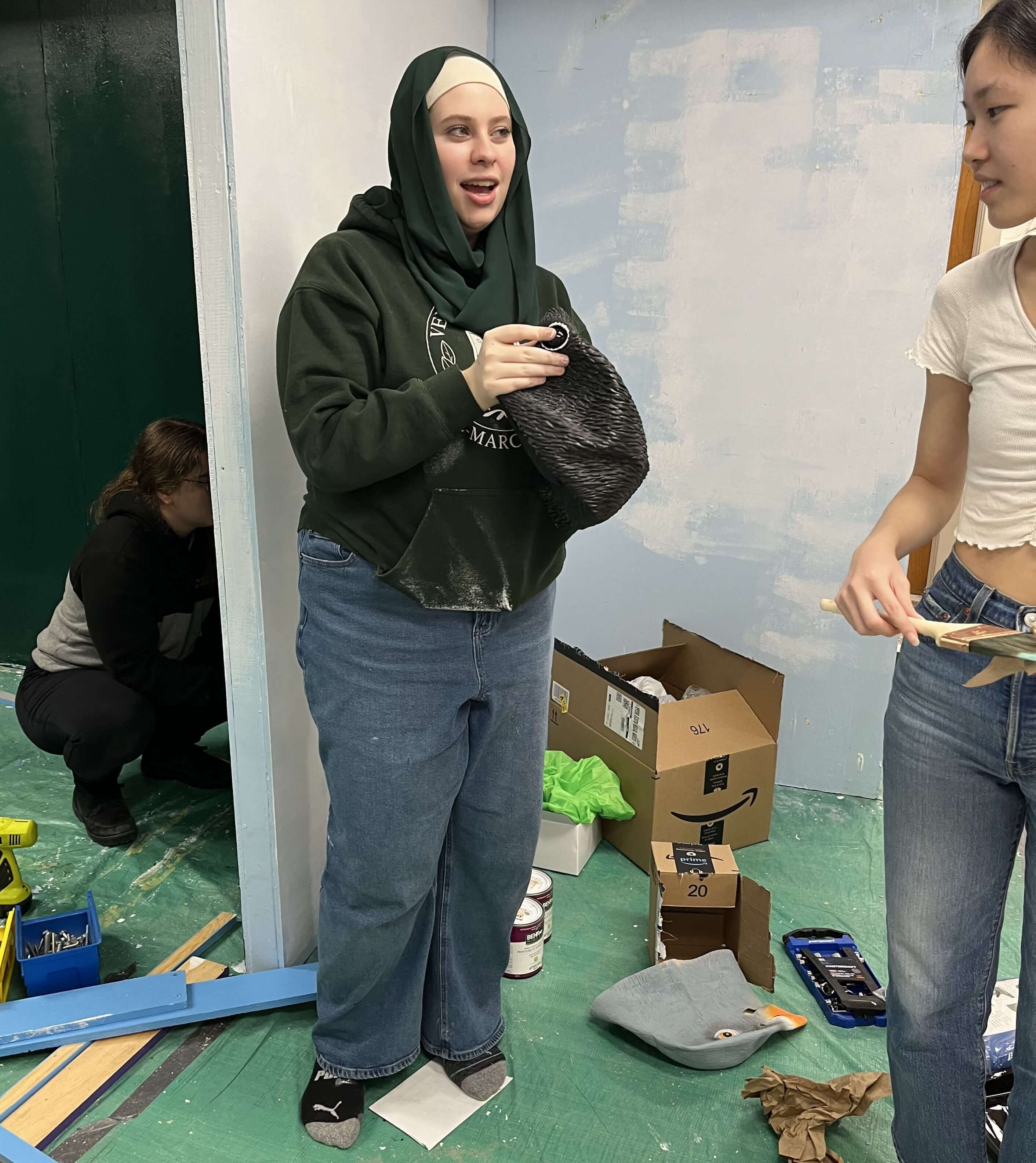 Three team members painting the kiosk walls.