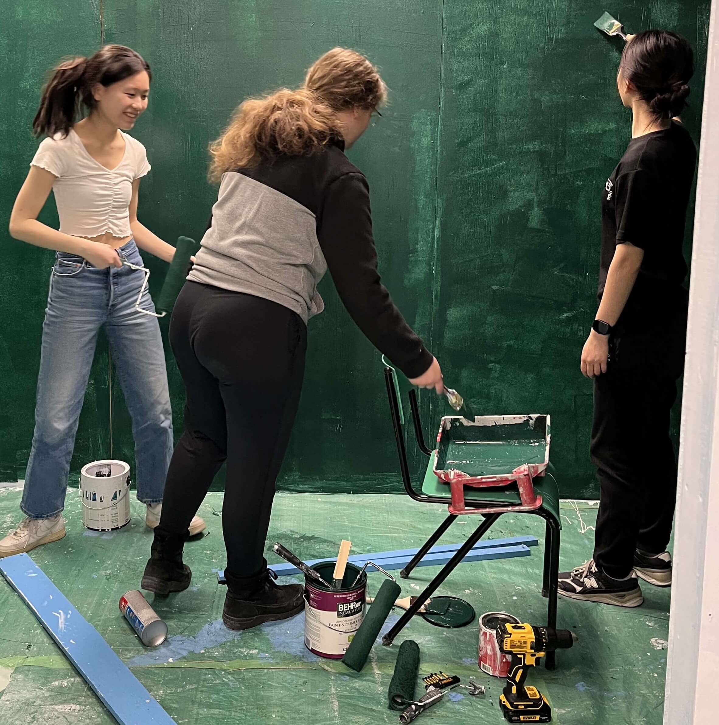 Three members of the team painting the kiosk in green.