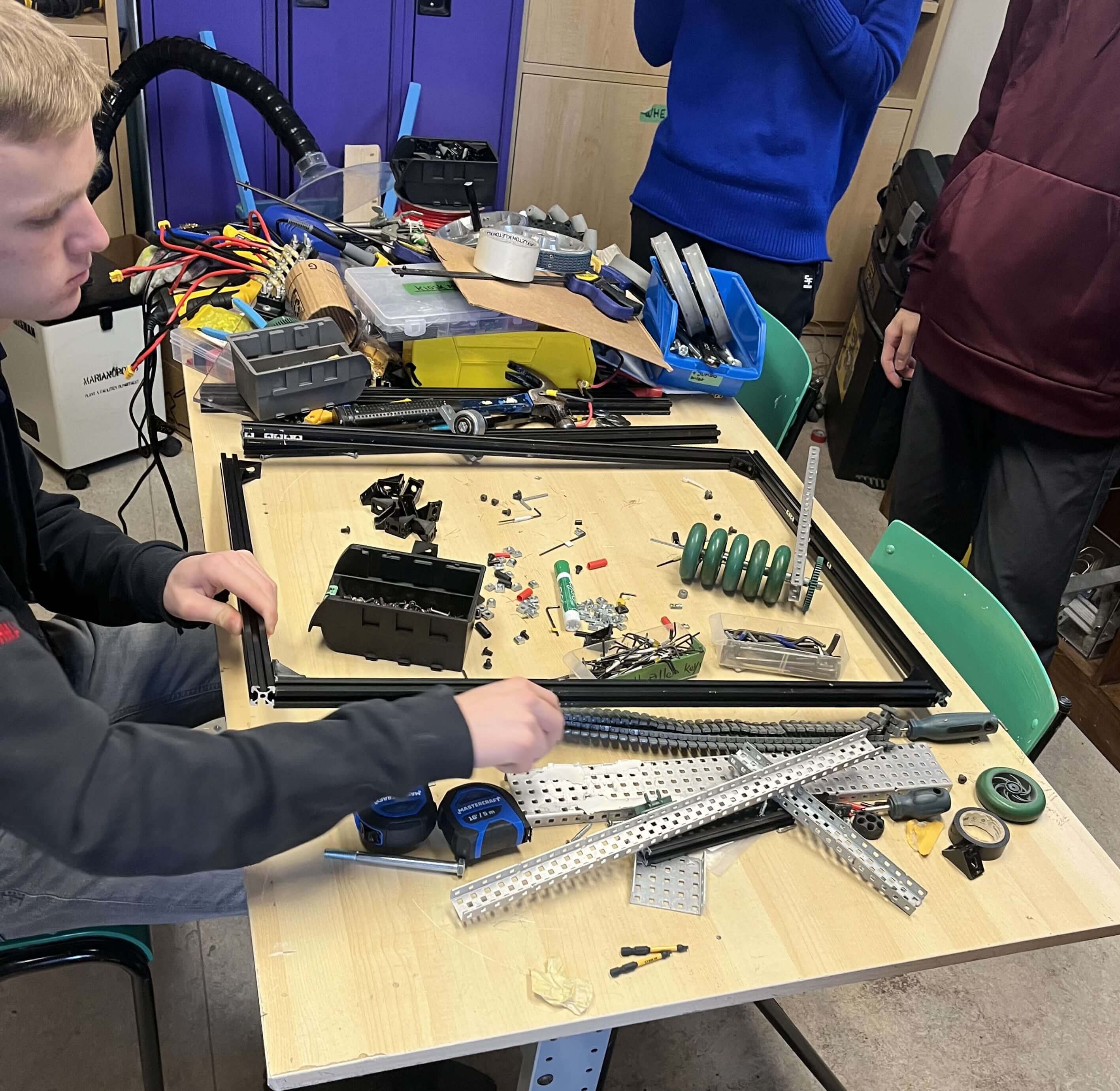 3 members of the robot team building the frame for the robot.